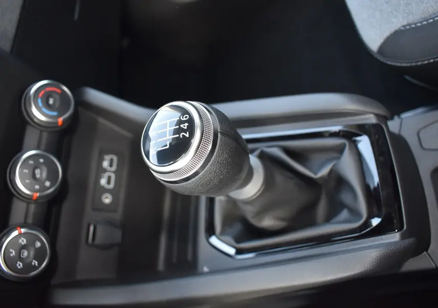 Le levier de vitesse manuel de la Renault Clio V TCE 90 gris, avec les commandes de climatisation en arrière-plan.