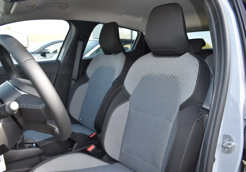 Vue intérieure de la Renault Clio V TCE 90 gris, mettant en valeur les sièges avant en tissu bicolore gris et noir.