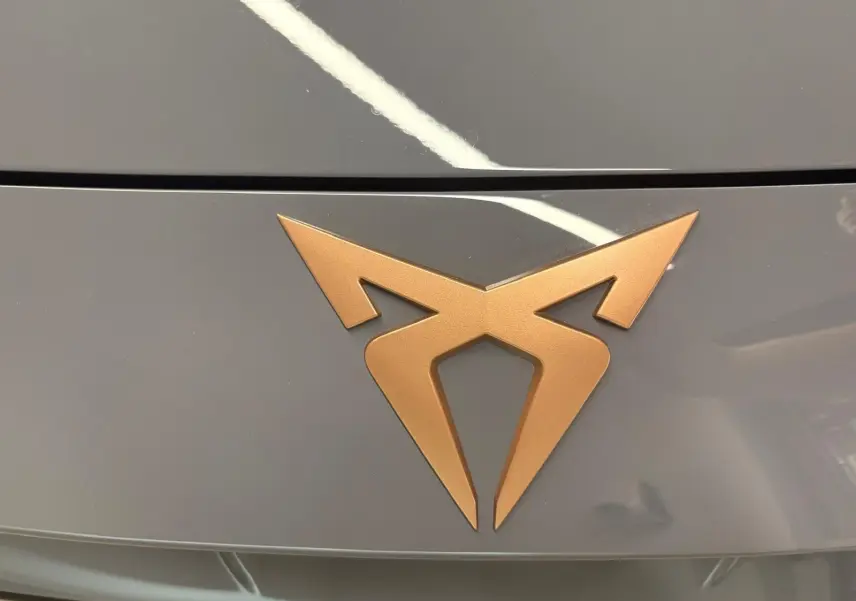 Gros plan sur le logo CUPRA bronze sur le capot gris graphène du Formentor 2025 avec toit ouvrant panoramique.