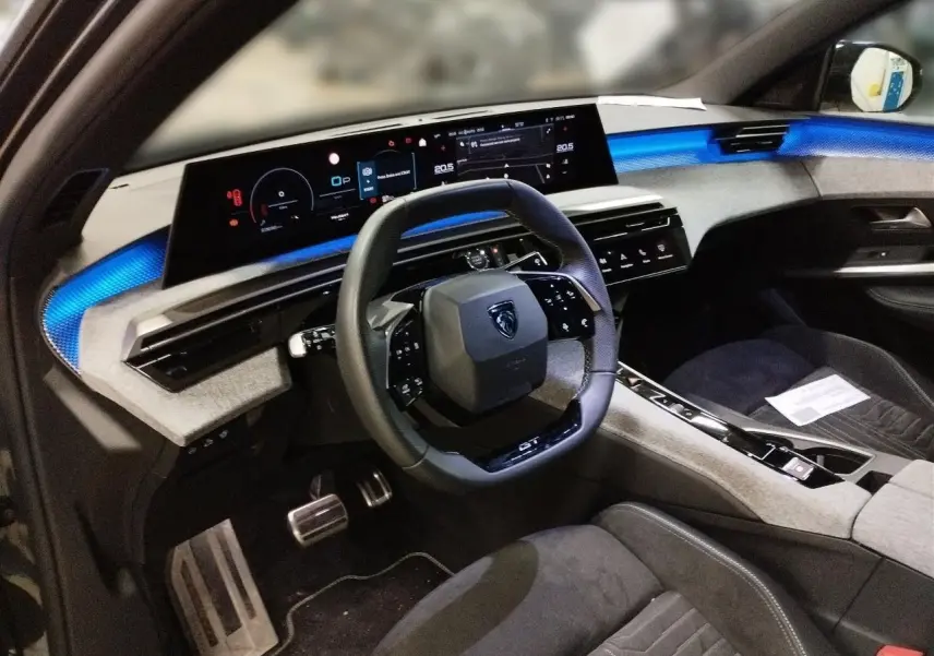 Vue intérieure côté conducteur du Peugeot 3008 Hybrid 145 e-DSC6 GT, tableau de bord avec éclairage bleu et volant compact noir.