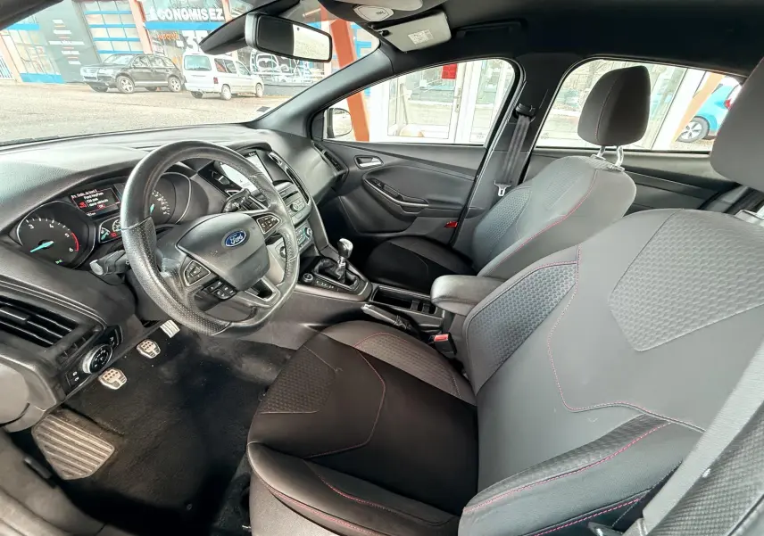 Gros plan sur les commandes de régulateur de vitesse au volant noir d'une Ford Focus gris 2018, version ST Line.