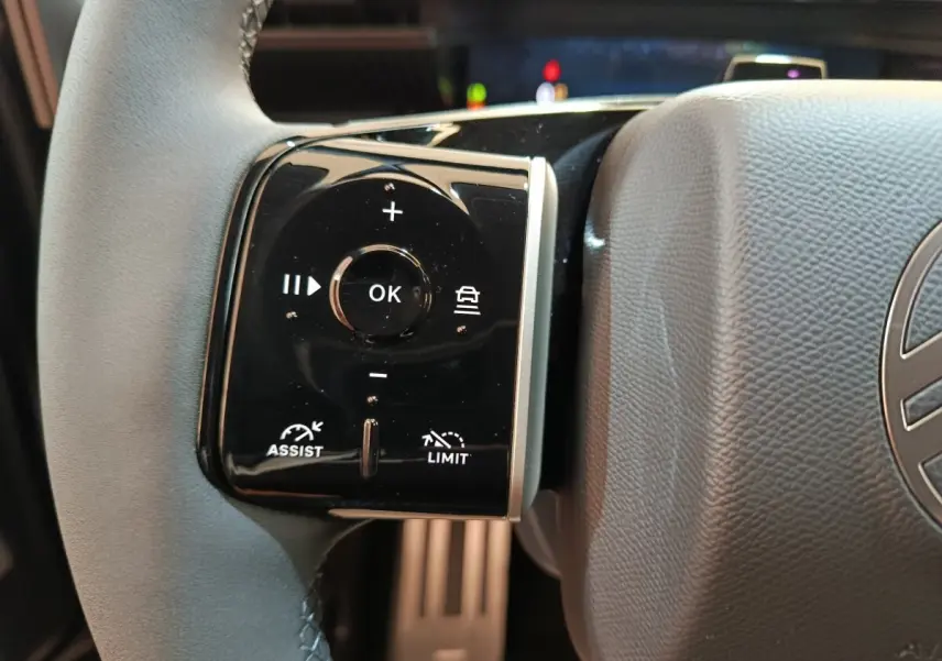 Gros plan sur la commande multifonctions gauche du volant cuir noir de la Citroën C5 Hybride 2026.
