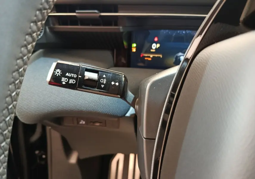 Gros plan sur la commande des phares et clignotants à gauche du volant dans l’habitacle noir du Citroën C5 Hybride 2026.
