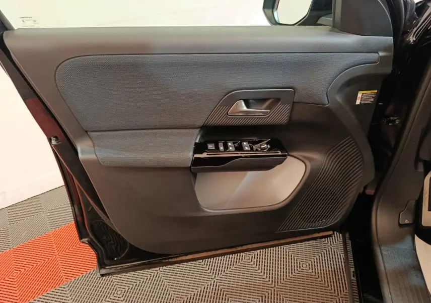 Vue intérieure côté gauche de la porte avant noire du Citroën C5 Hybride avec commandes de vitres et poignée intégrée.