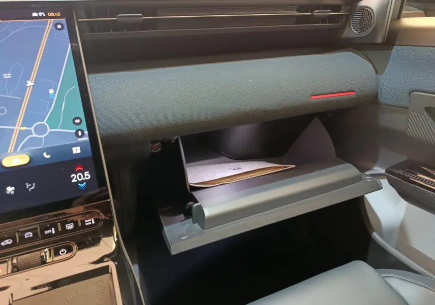 Intérieur de la CITROEN C5 Hybride 2026, vue du tableau de bord côté passager avec boîte à gants ouverte et écran tactile visible.