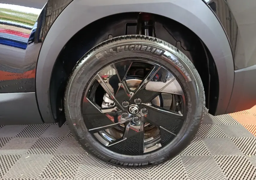 Gros plan sur la roue avant gauche noire brillante de la Citroën C5 Hybride 145ch auto MAX avec jante noire et pneu Michelin.