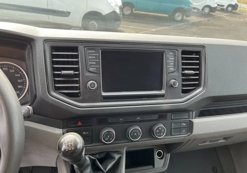 Tableau de bord du Volkswagen Crafter Fourgon 2019, vue frontale centrée sur l'écran tactile et levier de vitesses manuel.