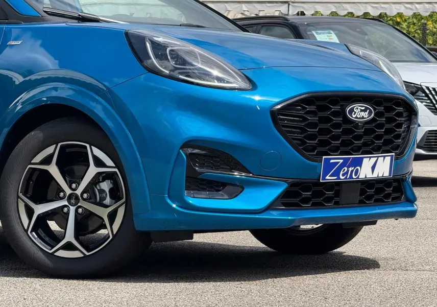 Vue de 3/4 avant droit d'une Ford Puma 2025 bleu Aqua avec calandre noire et jantes alliage distinctives.