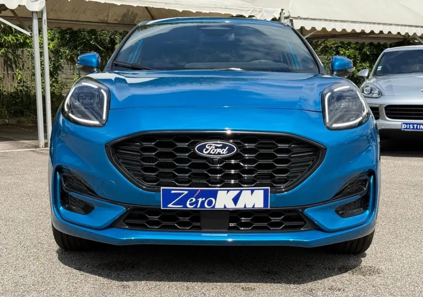 Vue frontale d'une Ford Puma 2025 en bleu aqua, avec calandre noire hexagonale et phares LED distinctifs.