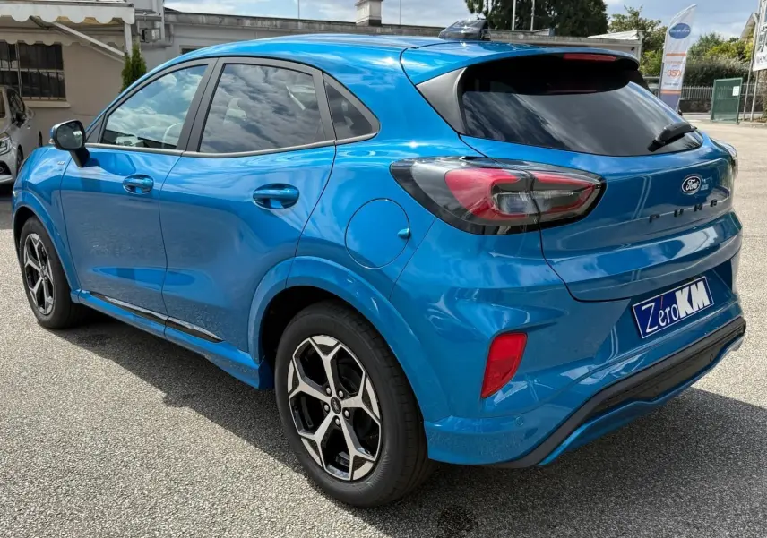 Ford Puma 2025 bleu Aqua Blue en vue 3/4 arrière droit, avec jantes alliage et vitres teintées.
