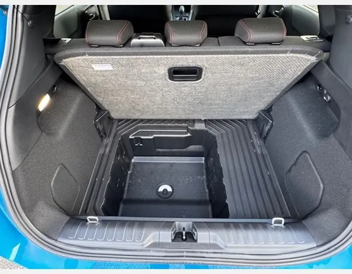 Coffre ouvert vu de l'arrière du Ford Puma bleu Aqua Blue 2025, montrant le rangement sous plancher et sièges arrière avec surpiqûres rouges.