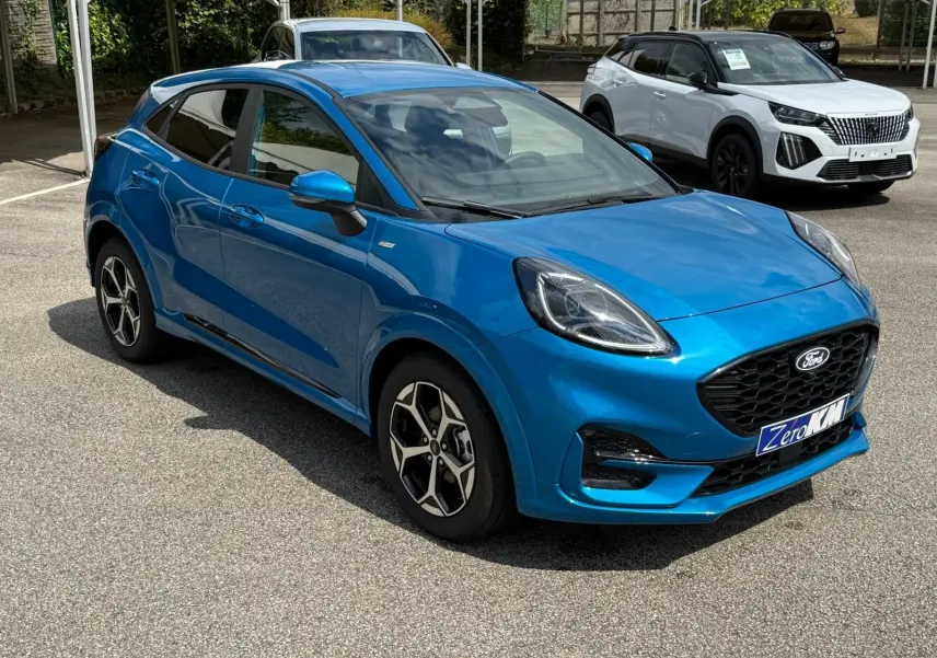 Ford Puma 2025 bleu Aqua Blue en 3/4 avant droit, avec jantes alliage et calandre noire distinctive.