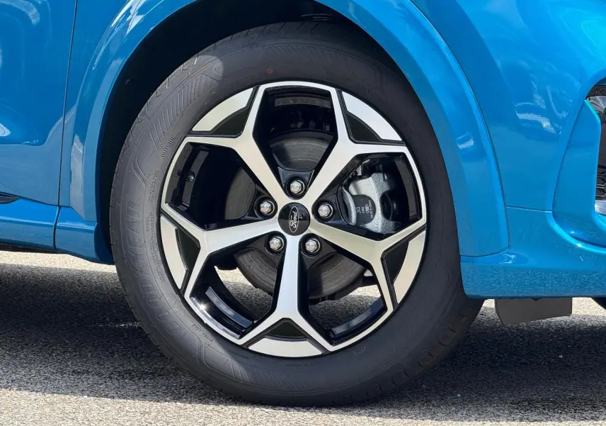 Gros plan sur la roue avant droite du Ford Puma bleu Aqua Blue avec jante alliage noire et argentée.