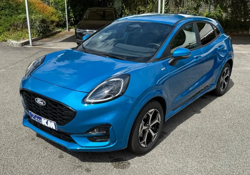 Ford Puma 2025 bleu aqua en vue 3/4 avant droit, avec calandre noire et jantes alliage distinctives.