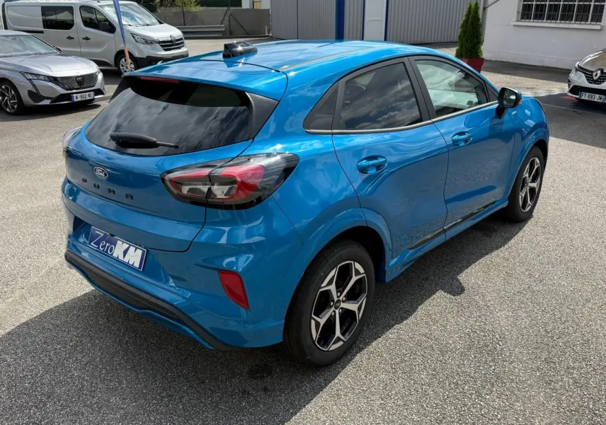 Vue 3/4 arrière droite d'une Ford Puma bleu aqua avec jantes alliage et vitres teintées sur parking.