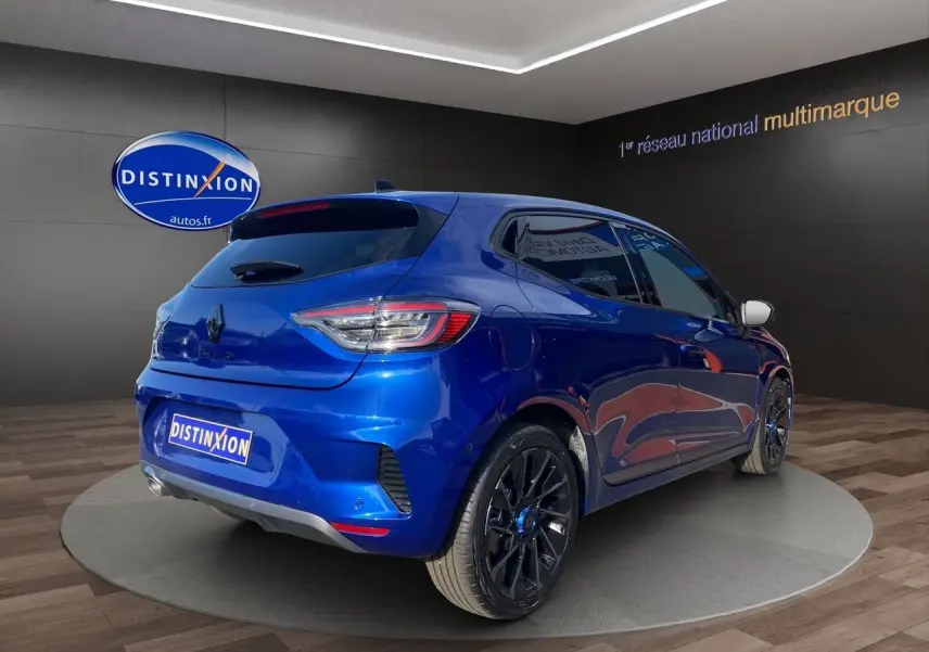 Vue 3/4 arrière droite d'une Renault Clio V TCE 90 Esprit Alpine bleu Iron avec jantes noires en showroom.