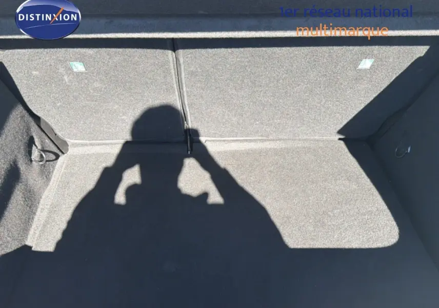 Coffre vide de la Renault Clio blanche 2025, vue de dessus montrant la moquette grise et les fixations internes.