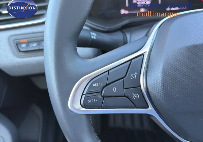 Gros plan sur les commandes au volant côté gauche d'une Renault Clio blanche, version 2025, avec finition noire.