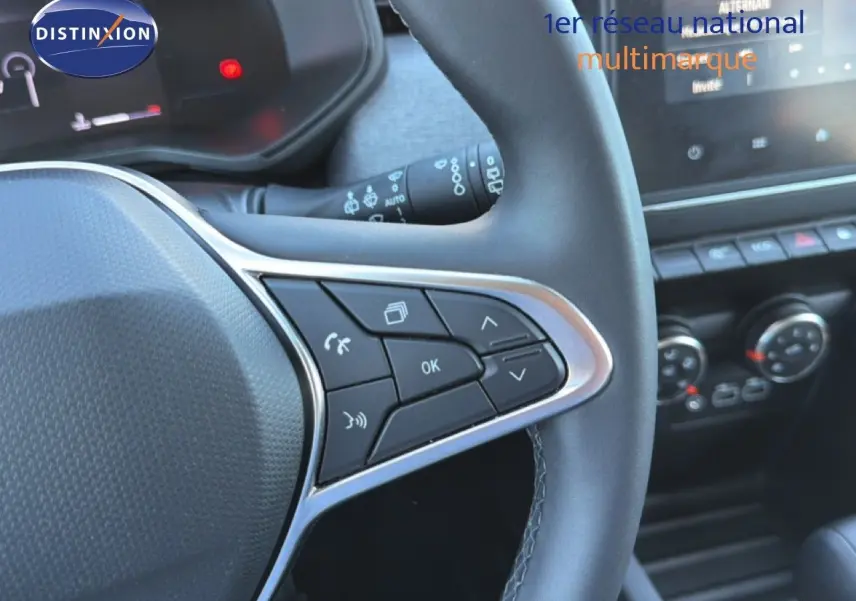 Gros plan sur le volant multifonction en cuir noir de la Renault Clio 2025, avec commandes intégrées et tableau de bord partiel.