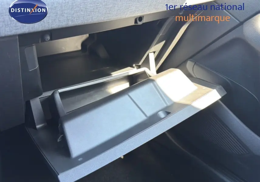 Gros plan sur la boîte à gants ouverte côté passager d'une Renault Clio blanche, intérieur noir visible.