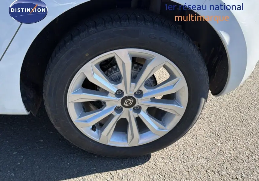 Gros plan sur la roue avant droite d'une Renault Clio blanche avec jante alliage à motif géométrique.