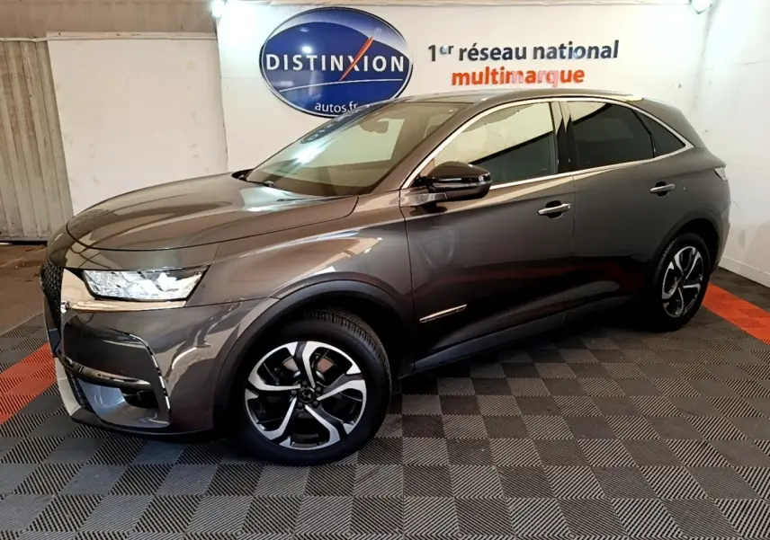 DS7 Crossback gris foncé en 3/4 avant droit, avec jantes alliage et feux LED dans un showroom intérieur.