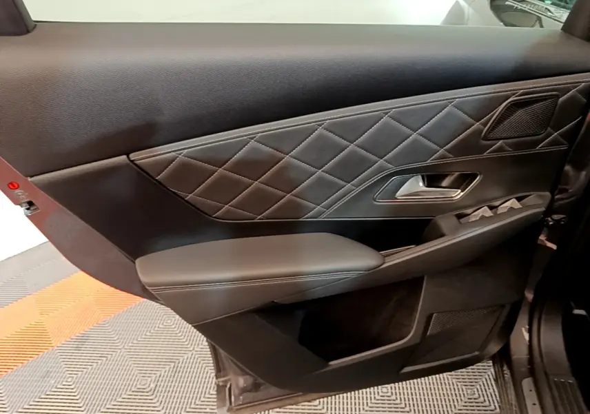 Gros plan sur la porte intérieure côté gauche du DS7 Crossback gris foncé, avec surpiqûres losanges et poignée argentée.