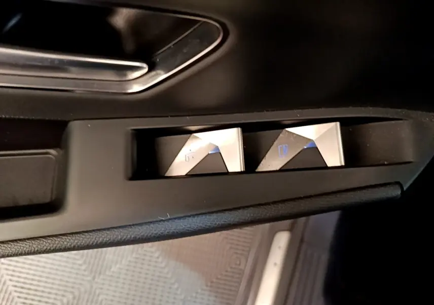 Boutons de commande des vitres électriques en métal brossé sur la portière côté conducteur d’un DS7 Crossback gris foncé.