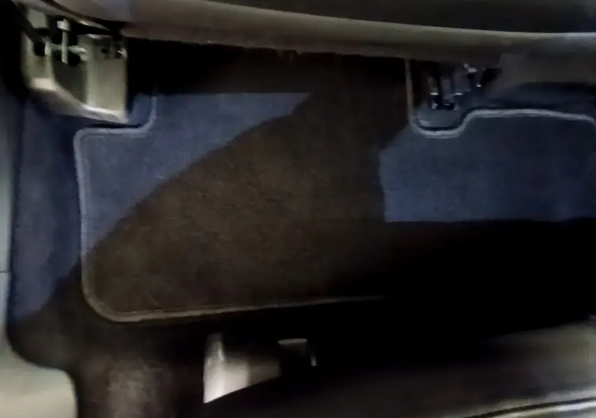 Vue rapprochée du tapis de sol côté conducteur du DS7 Crossback gris foncé, montrant les pédales et le repose-pied.