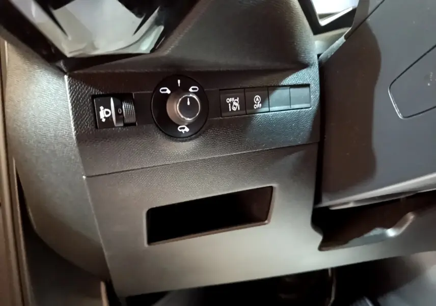 Détail intérieur montrant les commandes d’éclairage et d’assistance au conducteur sur le côté gauche du tableau de bord.