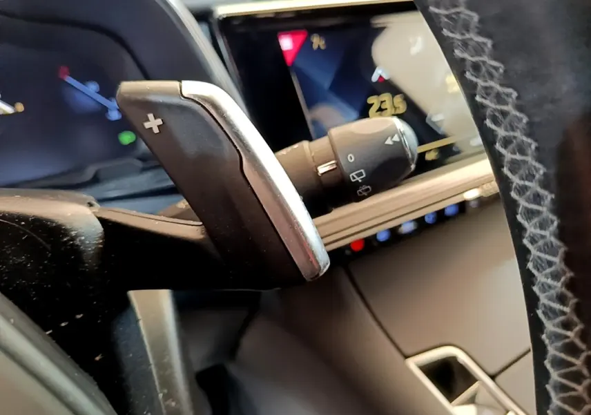 Gros plan sur la palette de changement de vitesse droite et le tableau de bord numérique du DS7 Crossback gris foncé.