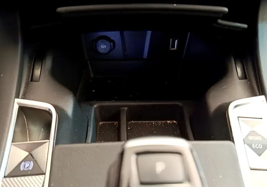 Gros plan sur la console centrale du DS7 Crossback gris foncé, avec bouton frein à main électrique et prises 12V et USB visibles.