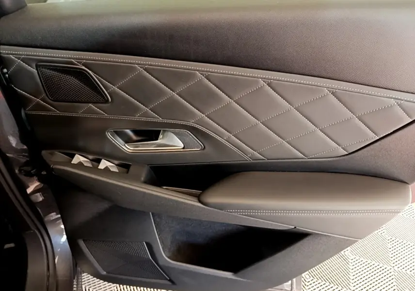 Gros plan sur la porte intérieure côté gauche du DS7 Crossback gris foncé avec surpiqûres et poignée métallique.