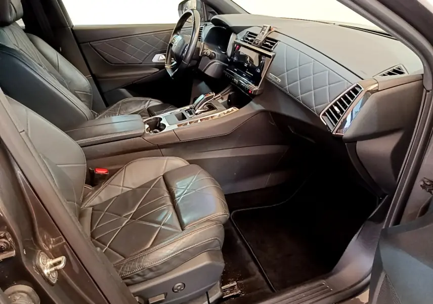 Vue intérieure côté conducteur du DS7 Crossback gris foncé, sièges cuir matelassé et tableau de bord moderne avec écran tactile.
