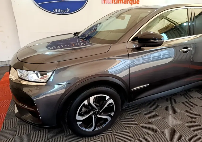 Vue 3/4 avant droit du DS7 Crossback gris foncé, mettant en valeur ses phares LED et jantes alliage bicolores.