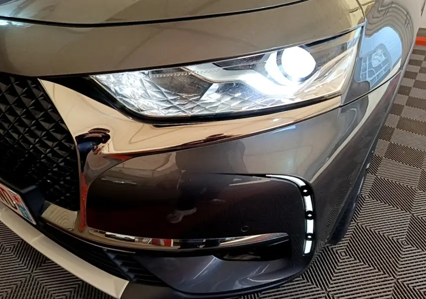 Gros plan sur l'avant droit gris foncé du DS7 Crossback 2019, mettant en valeur le phare LED et la calandre chromée.