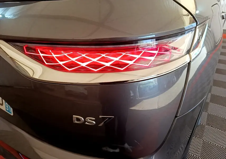 Gros plan sur le feu arrière droit rouge à motif losange du DS7 Crossback gris foncé, avec logo DS7 visible.