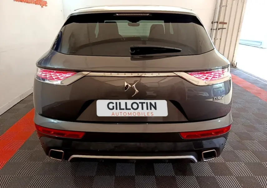 Vue arrière d'un DS7 Crossback gris foncé avec feux LED et double sortie d'échappement carrée, en intérieur showroom.