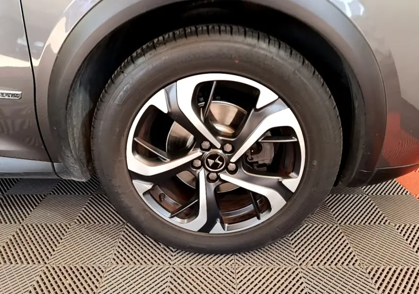 Gros plan sur la roue avant gauche du DS7 Crossback gris foncé, mettant en valeur la jante alliage à cinq branches doubles.