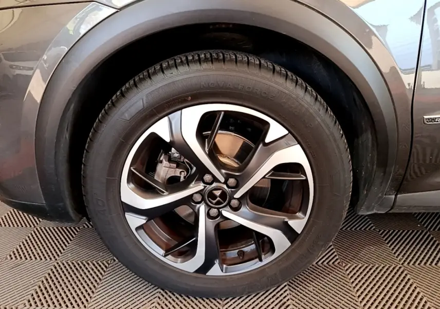 Gros plan sur la roue avant gauche et la jante en alliage du DS7 Crossback gris foncé, avec logo DS visible.