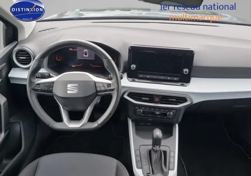 Vue intérieure frontale du tableau de bord et volant cuir méplat de la SEAT Arona 2025 gris magnétique avec écran tactile et console centrale.