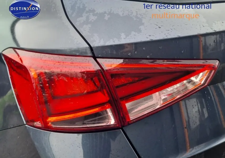 Gros plan sur le feu arrière droit rouge du SEAT Arona gris magnétique 2025 sous la pluie.