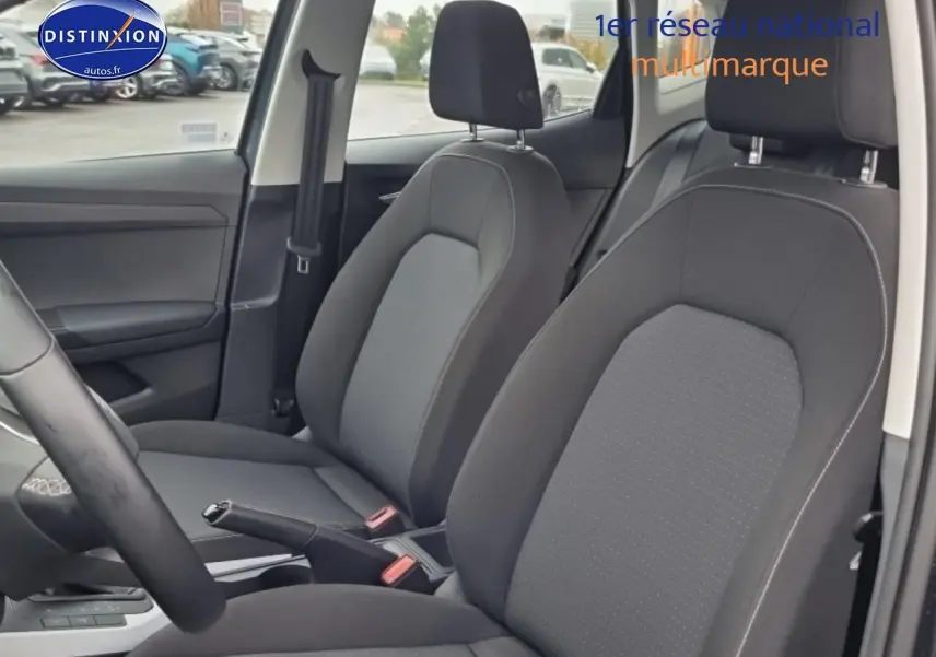 Vue intérieure côté avant droit du SEAT Arona 2025 avec sièges tissu gris Como et volant multifonction cuir méplat.
