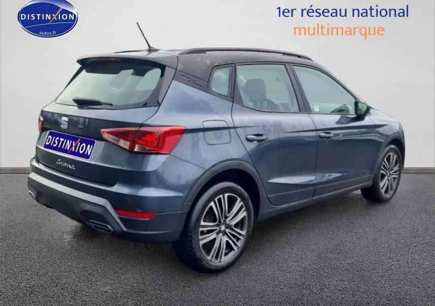 Vue 3/4 arrière droite d'un SEAT Arona gris magnétique avec jantes 17 pouces et barres de toit noires.