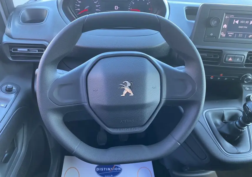 Vue rapprochée du volant Peugeot noir et du tableau de bord avec levier de vitesses manuel du Partner Fourgon 2025.