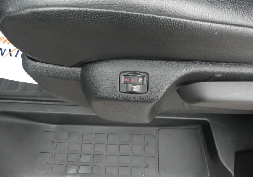 Gros plan sur le bouton de siège chauffant noir sous le siège avant du Peugeot Expert Fourgon blanc.