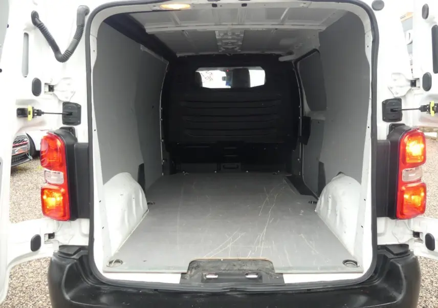 Vue arrière du Peugeot Expert Fourgon blanc 2019 avec portes ouvertes et plancher bois visible dans l’espace de chargement.