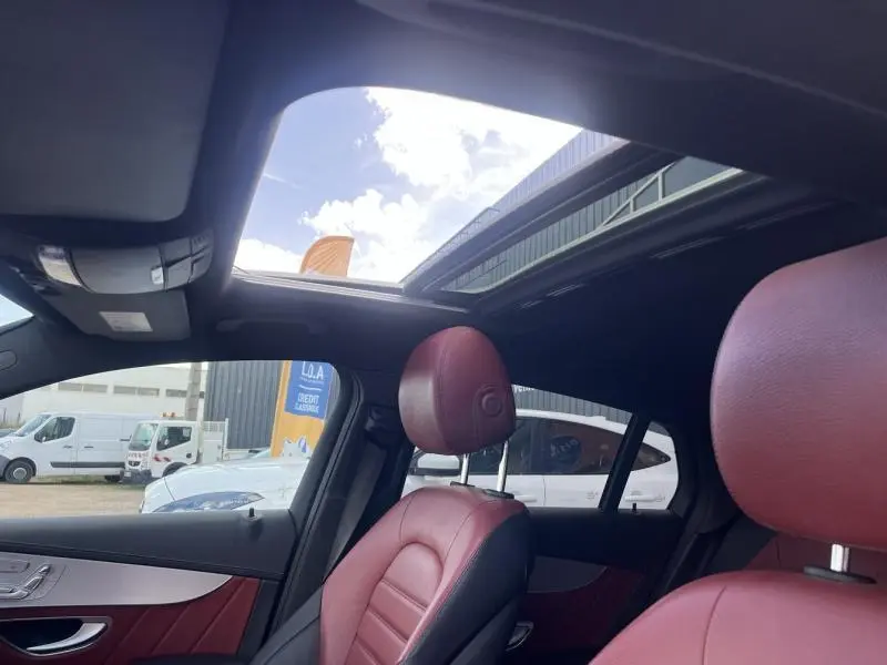Intérieur d'un Mercedes GLC Coupé blanc diamant, vue sur sièges cuir rouge/noir et toit ouvrant panoramique.