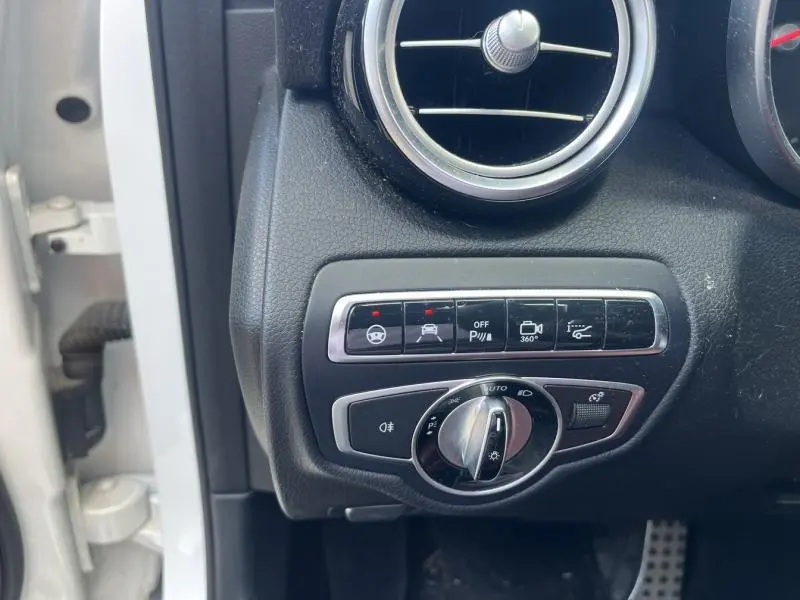 Gros plan sur les commandes d'assistance et éclairage à gauche du tableau de bord d'un Mercedes GLC Coupé blanc diamant.