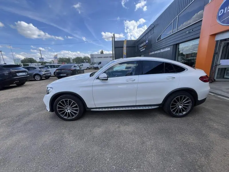 Profil côté gauche d'un Mercedes GLC Coupé blanc diamant brillant designo avec jantes AMG multibranches bicolores.